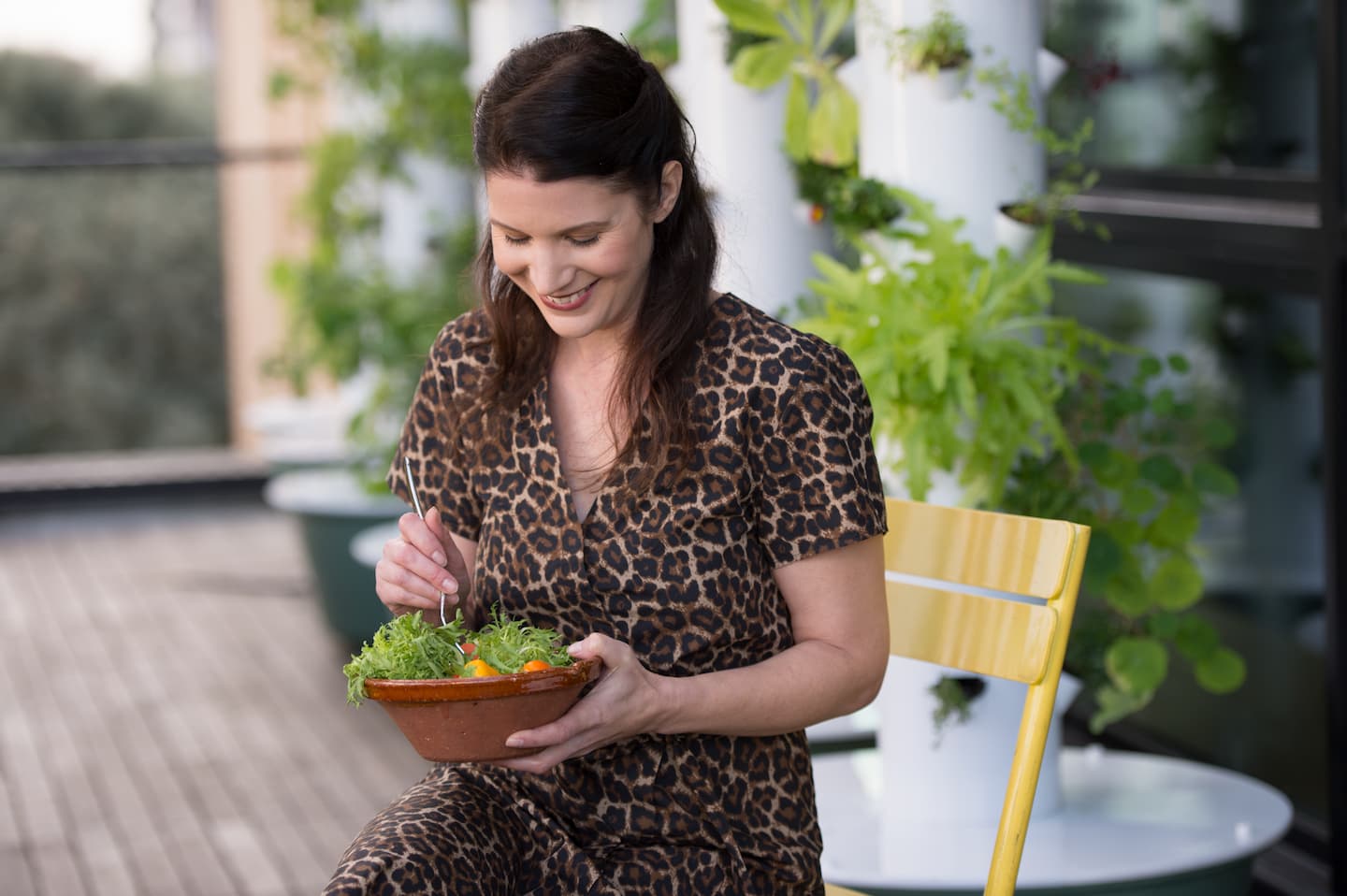 A laughing woman is eating salad