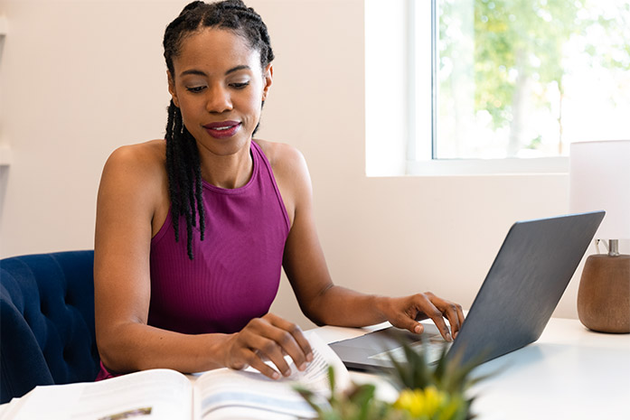 Woman in pink tank top sitting in front of laptop