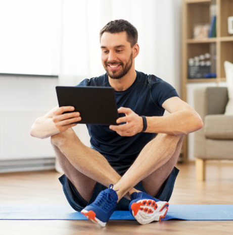 Man sitting on floor holding an Ipad smiling