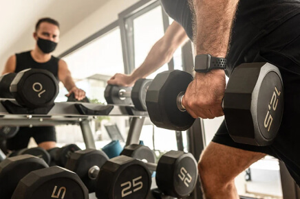 Male wearing a face mask doing a dumbbell bent over row