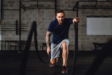 Male doing back lunge battle rope workout