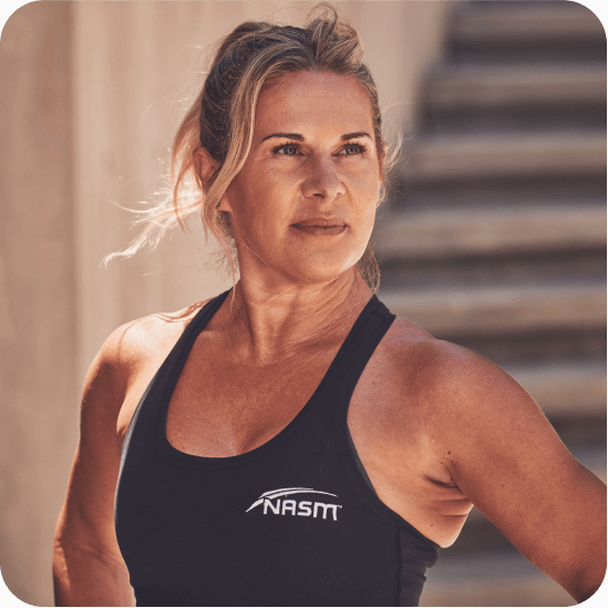 Female NASM trainer posing towards camera with cement stairs behind