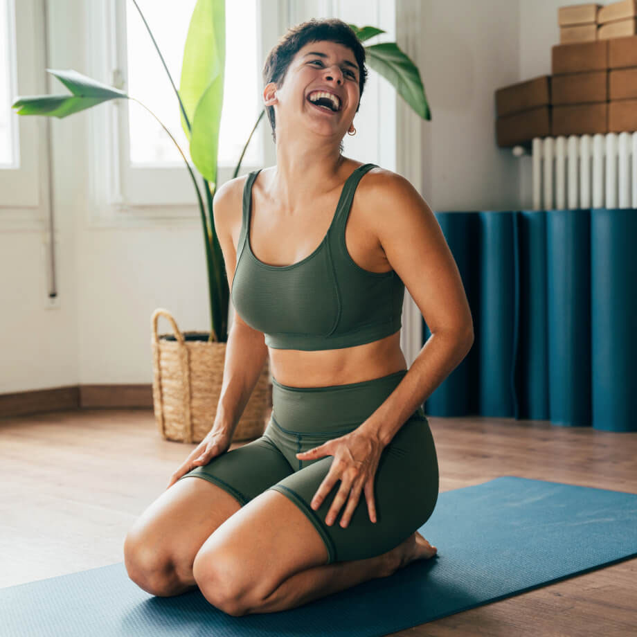 A woman kneeling on a mat laughing