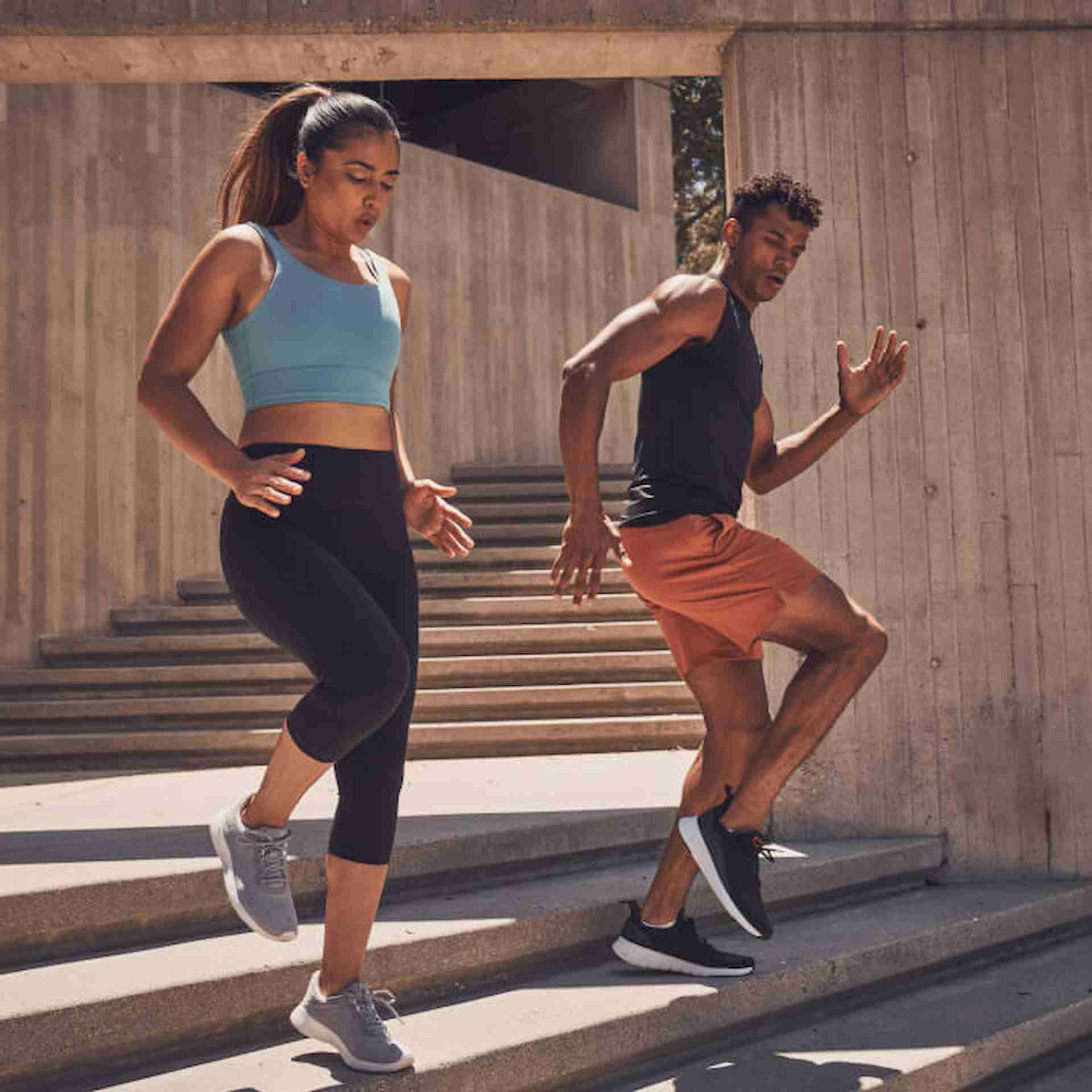 Male NASM trainer running down concrete steps with female client