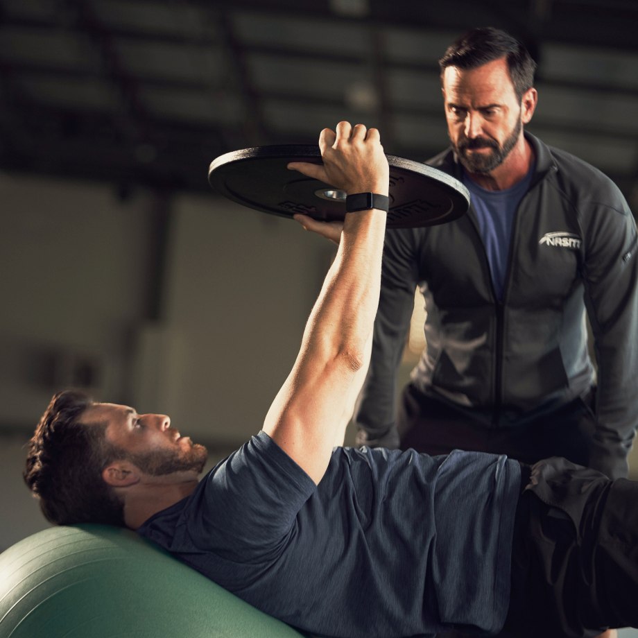 Male NASM trainer training male client on a medicine ball