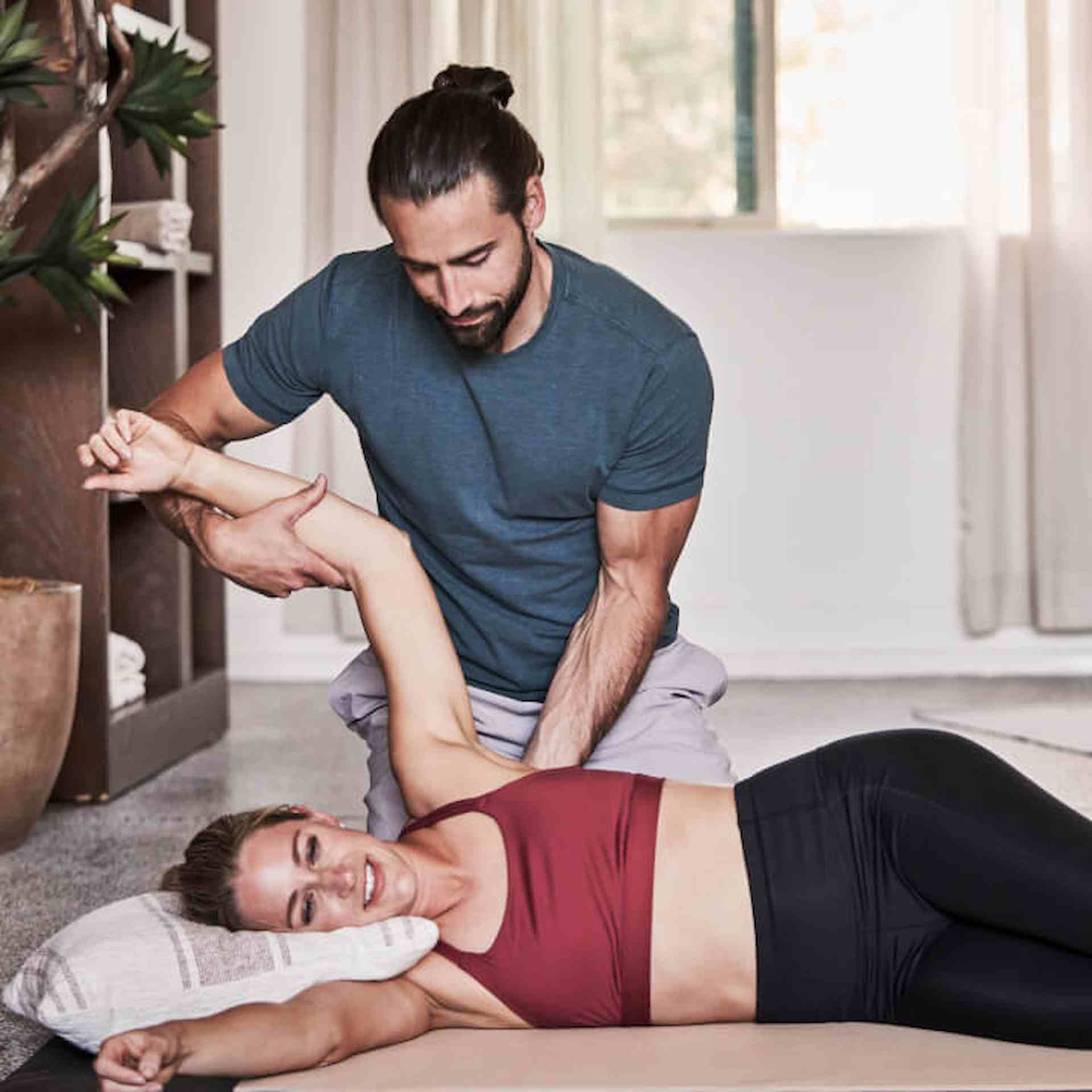 A male coach helping a female client stretch