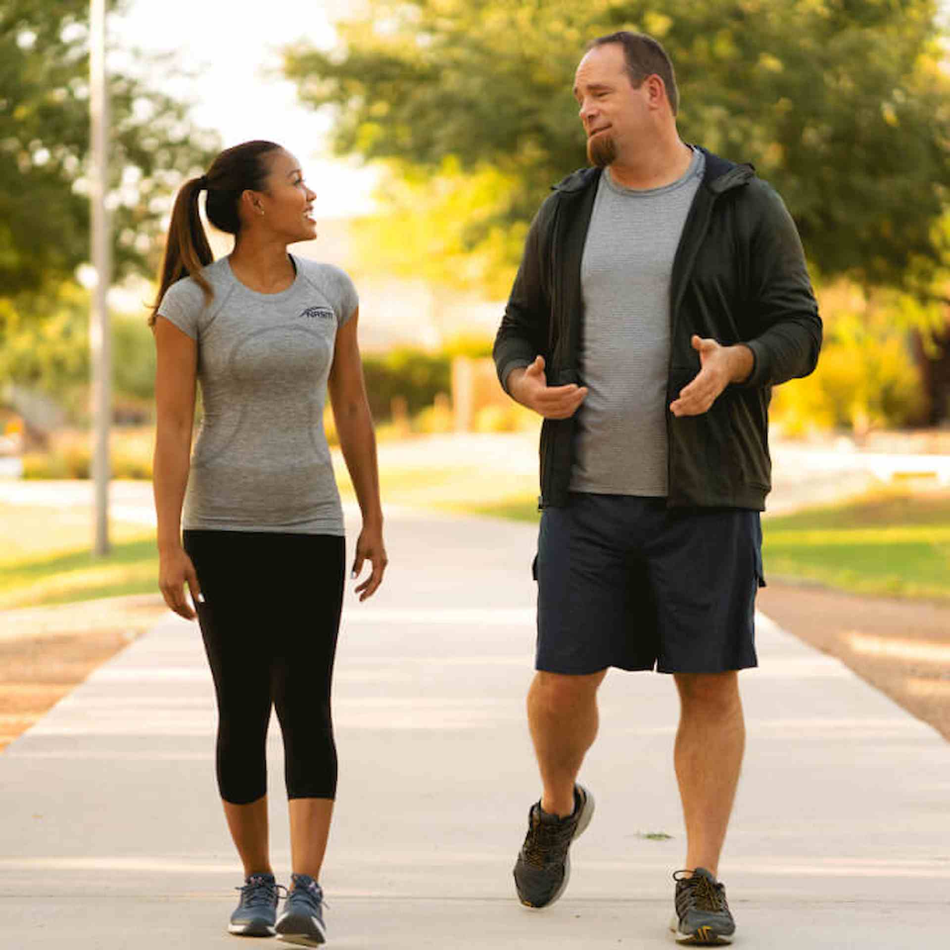 Two women wearing workout gear are standing and talking